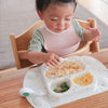 ハイチェアに座り、EasyMatミニに盛られた食事をフォークで食べる子どもの写真