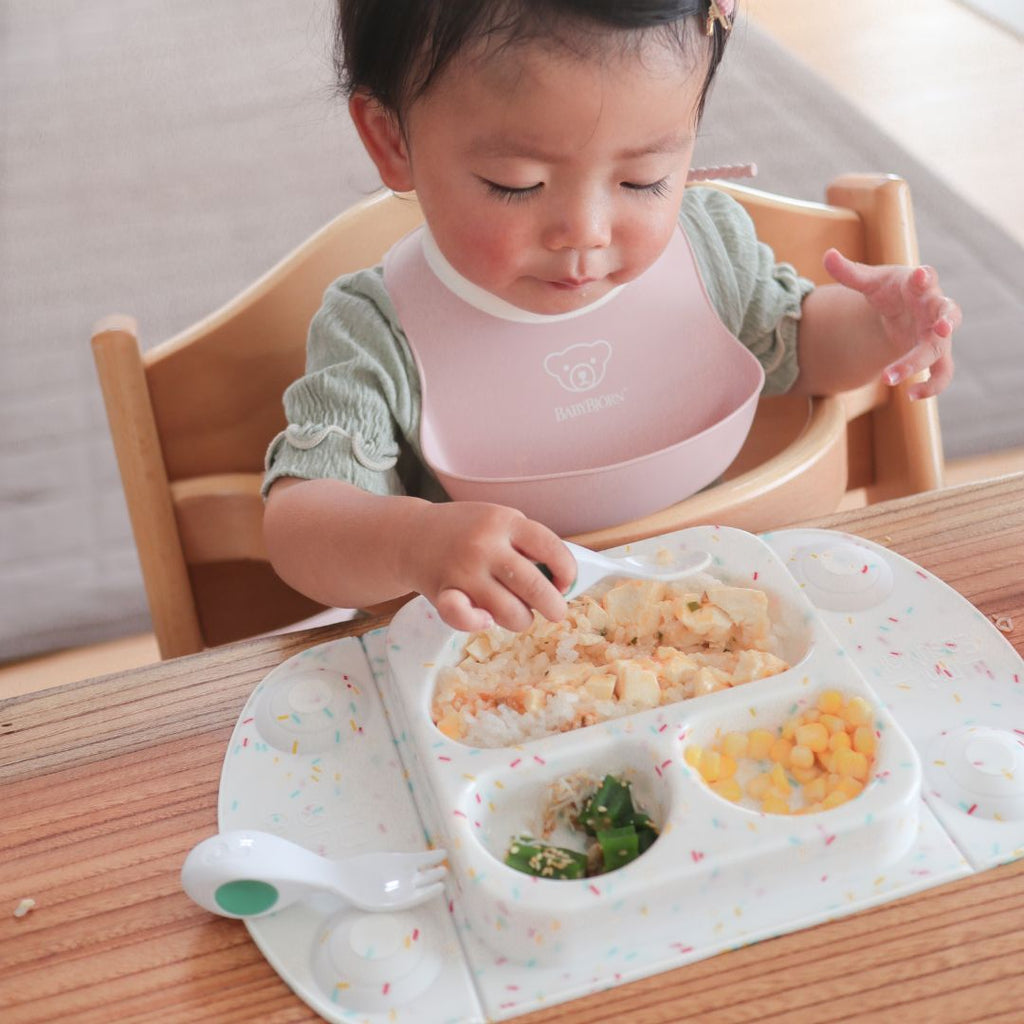ハイチェアに座り、EasyMatミニに盛られた食事をフォークで食べる子どもの写真