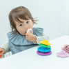 子どもがレインボースタッカーを口に運びながら遊んでいる写真